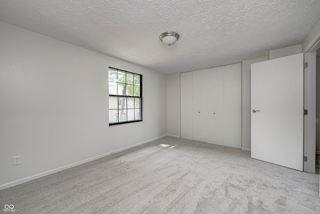 unfurnished bedroom with a closet, light carpet, and a textured ceiling