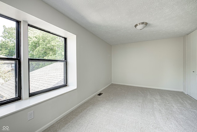 carpeted spare room featuring a textured ceiling