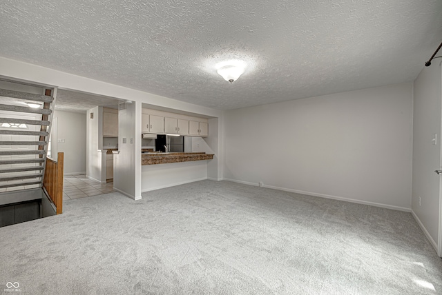 unfurnished living room with a textured ceiling and light carpet