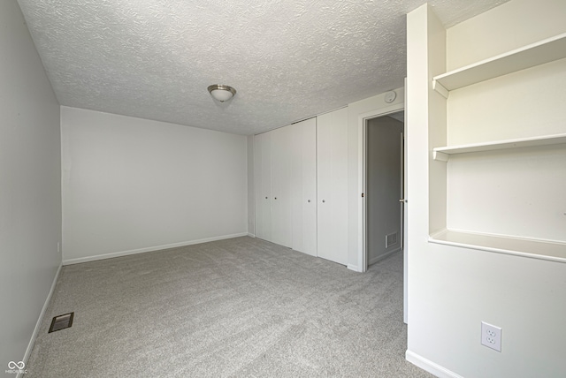 spare room with light carpet and a textured ceiling