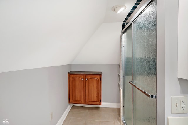 bathroom with lofted ceiling, tile patterned flooring, and a shower with shower door