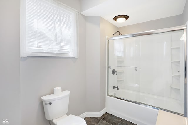 bathroom with tile patterned flooring, toilet, and bath / shower combo with glass door