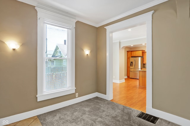 spare room with plenty of natural light, ornamental molding, and light hardwood / wood-style floors