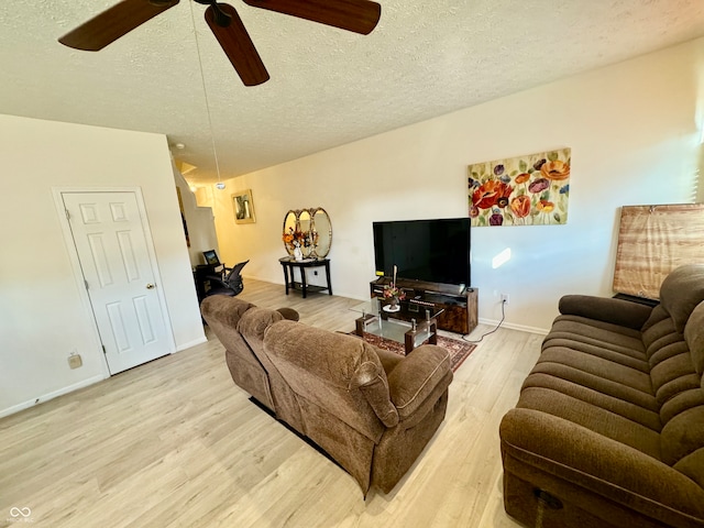 living room featuring light hardwood / wood-style flooring, ceiling fan, and a textured ceiling