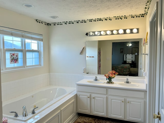 bathroom featuring vanity, a textured ceiling, and a relaxing tiled tub