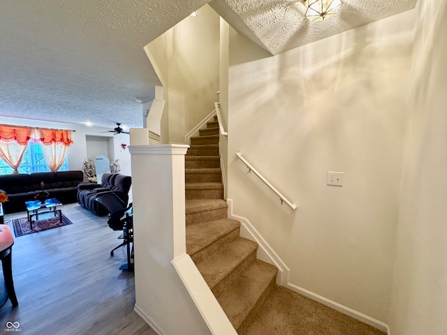 stairs with a textured ceiling, hardwood / wood-style flooring, and ceiling fan