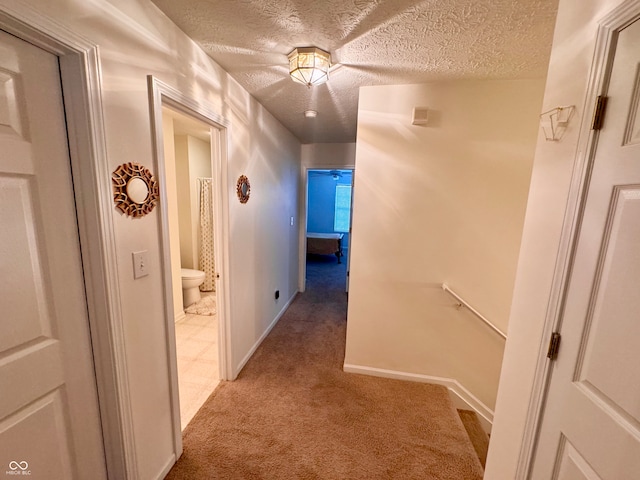 hallway with a textured ceiling and light colored carpet