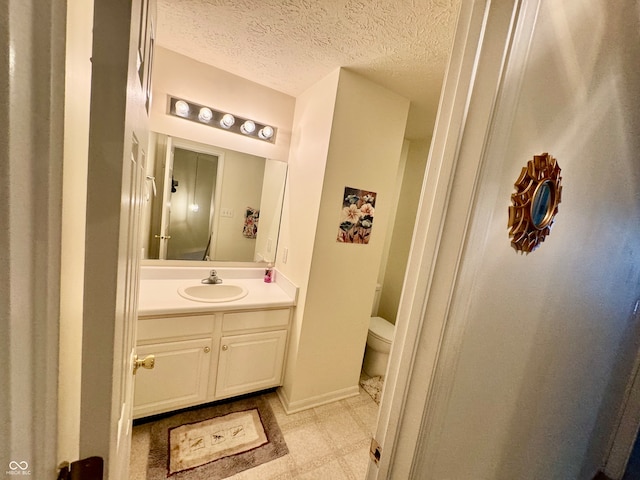 bathroom featuring a textured ceiling, vanity, and toilet