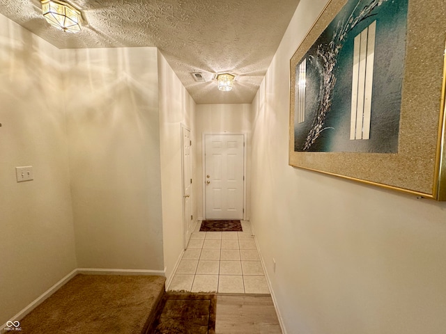 corridor with a textured ceiling and carpet flooring