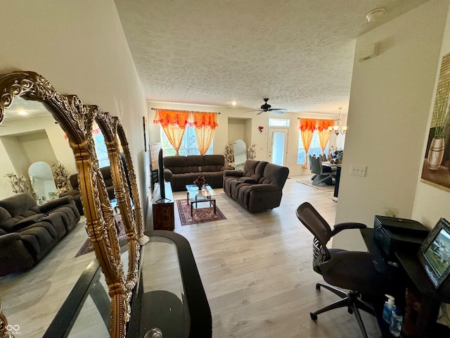 living room featuring light hardwood / wood-style flooring, a textured ceiling, and ceiling fan with notable chandelier