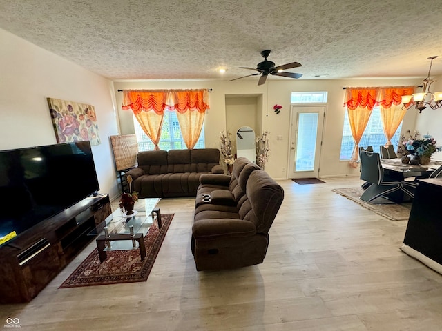 living room featuring a textured ceiling, ceiling fan with notable chandelier, and light wood-type flooring