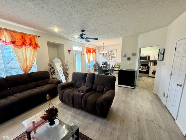 living room featuring light hardwood / wood-style flooring, a textured ceiling, and ceiling fan with notable chandelier