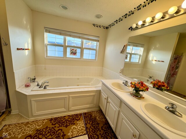 bathroom with vanity, a textured ceiling, tile patterned flooring, and a bath