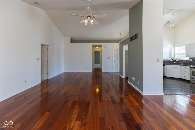 unfurnished living room with baseboards, dark wood finished floors, high vaulted ceiling, a ceiling fan, and a sink