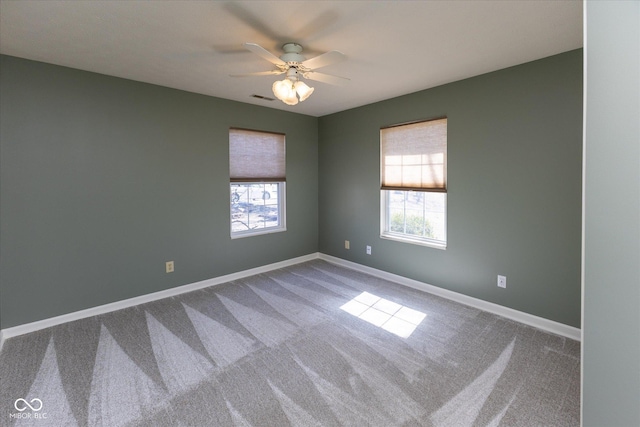 carpeted empty room featuring ceiling fan, a healthy amount of sunlight, visible vents, and baseboards