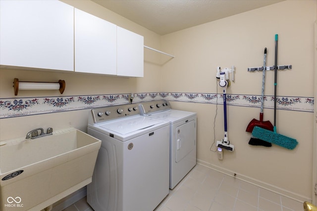 laundry area with a sink, a textured ceiling, cabinet space, separate washer and dryer, and baseboards