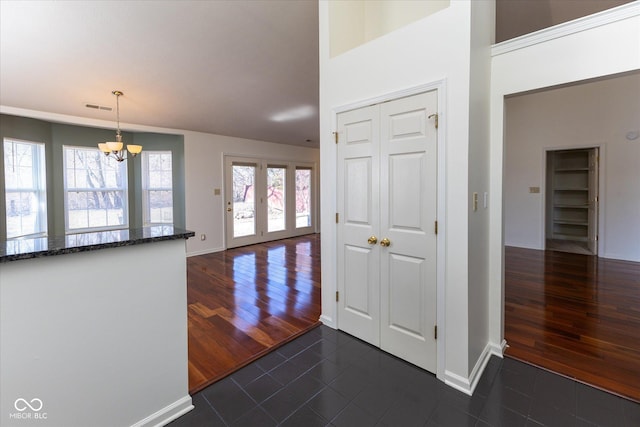 hall featuring baseboards, visible vents, an inviting chandelier, a high ceiling, and dark wood-style flooring