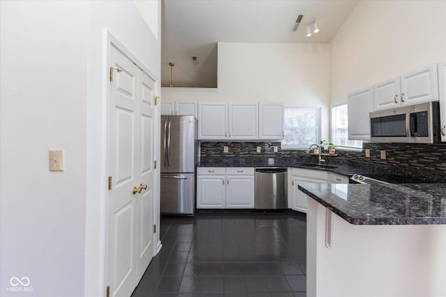 kitchen featuring dark tile patterned flooring, white cabinets, backsplash, and stainless steel appliances