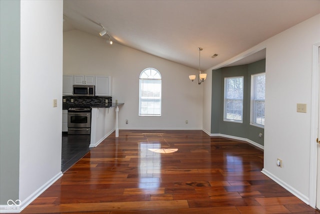 kitchen featuring decorative backsplash, vaulted ceiling, dark wood-style floors, and stainless steel appliances