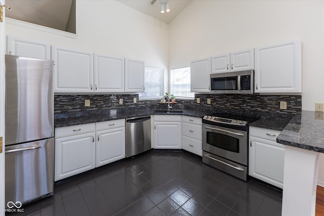 kitchen featuring tasteful backsplash, white cabinets, stainless steel appliances, and a sink