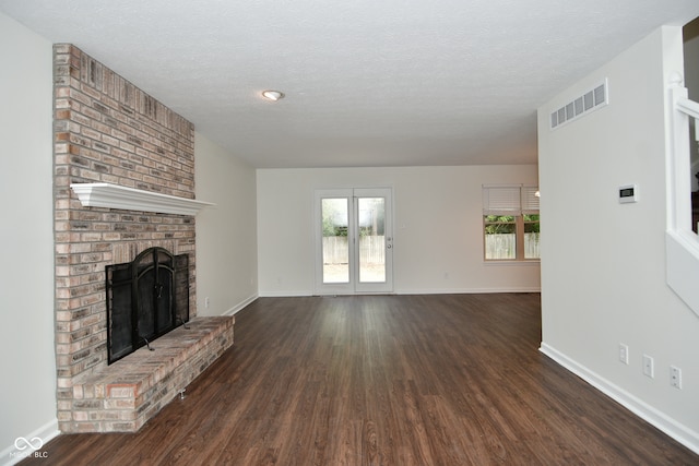 unfurnished living room featuring plenty of natural light, dark hardwood / wood-style flooring, and a brick fireplace