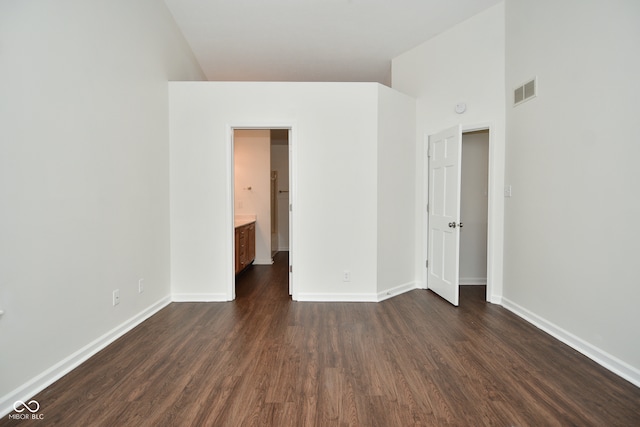 unfurnished bedroom with dark hardwood / wood-style flooring, high vaulted ceiling, and ensuite bath