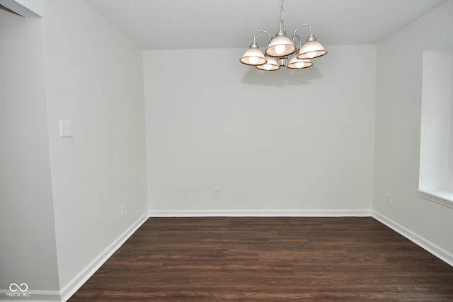 unfurnished room with a notable chandelier and dark hardwood / wood-style floors