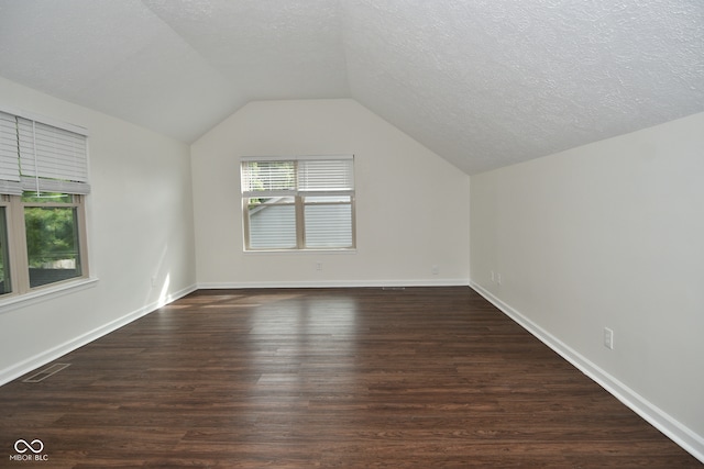 bonus room with lofted ceiling, plenty of natural light, and dark wood-type flooring