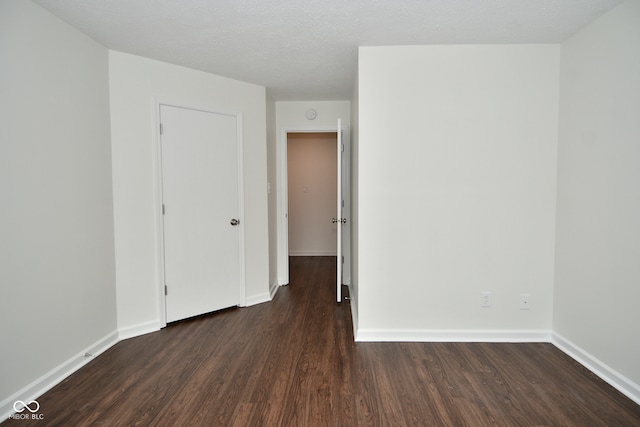 unfurnished room featuring a textured ceiling and dark hardwood / wood-style floors