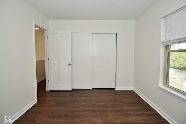 unfurnished bedroom with dark wood-type flooring and a closet