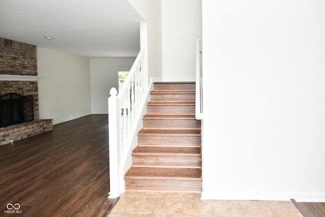 staircase featuring hardwood / wood-style flooring and a fireplace