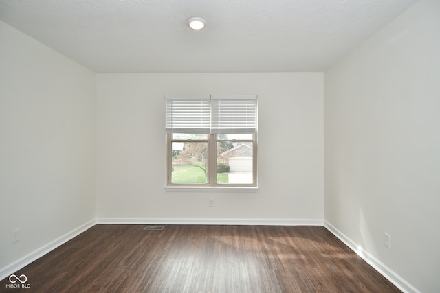 spare room featuring a textured ceiling and dark wood-type flooring