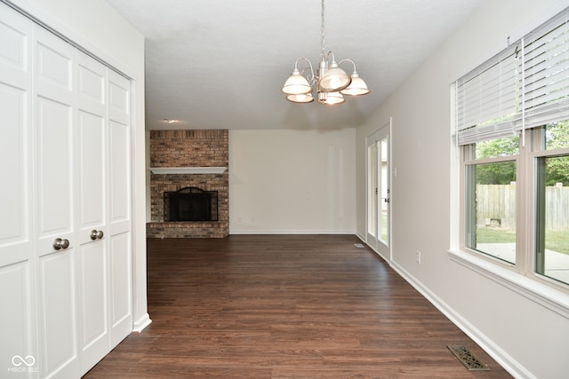 unfurnished living room with a fireplace, plenty of natural light, and dark hardwood / wood-style floors