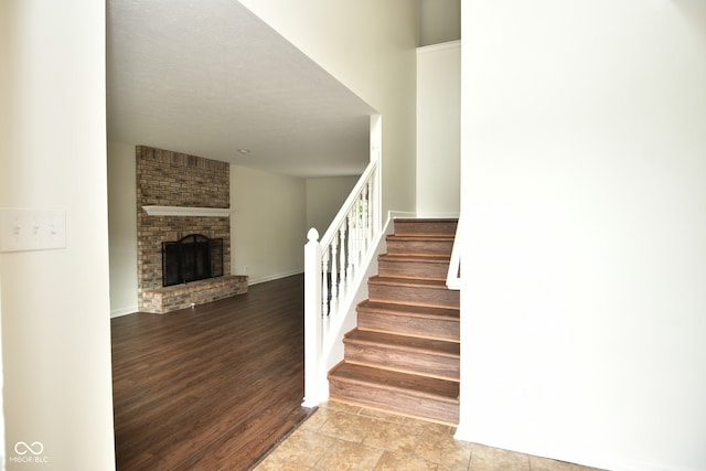 stairway featuring a textured ceiling, hardwood / wood-style floors, and a brick fireplace