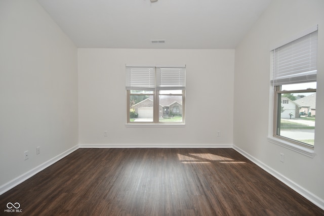 empty room with dark hardwood / wood-style flooring and plenty of natural light