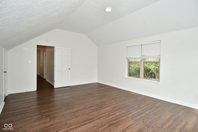 additional living space with vaulted ceiling, a textured ceiling, and dark hardwood / wood-style flooring