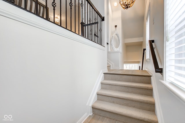 stairway with a notable chandelier and hardwood / wood-style flooring