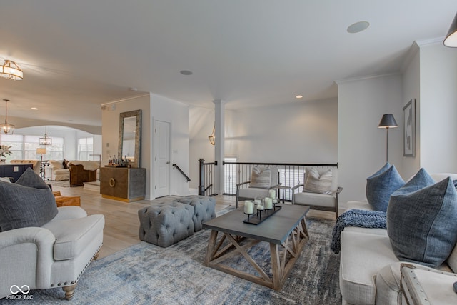 living room with ornamental molding, a wealth of natural light, a notable chandelier, and light wood-type flooring