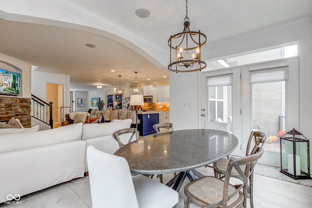 dining area with light hardwood / wood-style floors, an inviting chandelier, and ornamental molding