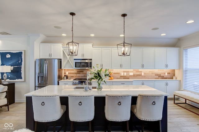 kitchen featuring hanging light fixtures, a center island with sink, light hardwood / wood-style flooring, and appliances with stainless steel finishes