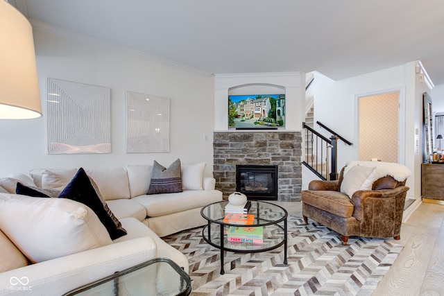 living room featuring crown molding, a fireplace, and light wood-type flooring