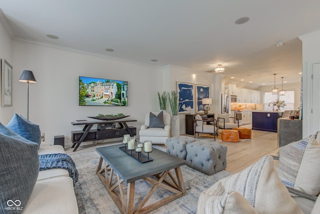 living room featuring an inviting chandelier, light hardwood / wood-style floors, and ornamental molding