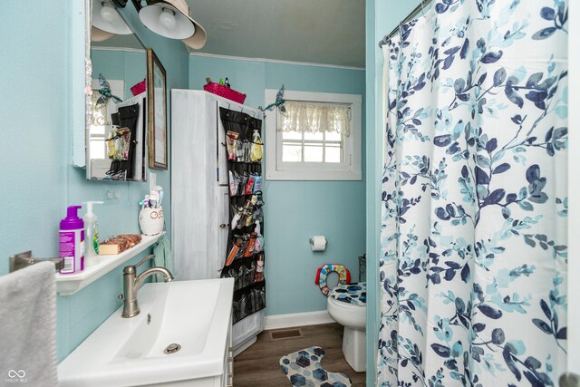 bathroom featuring wood-type flooring, toilet, crown molding, and vanity