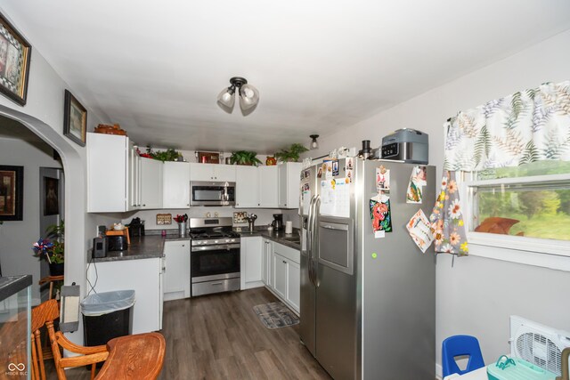 kitchen with appliances with stainless steel finishes, white cabinets, and dark hardwood / wood-style floors