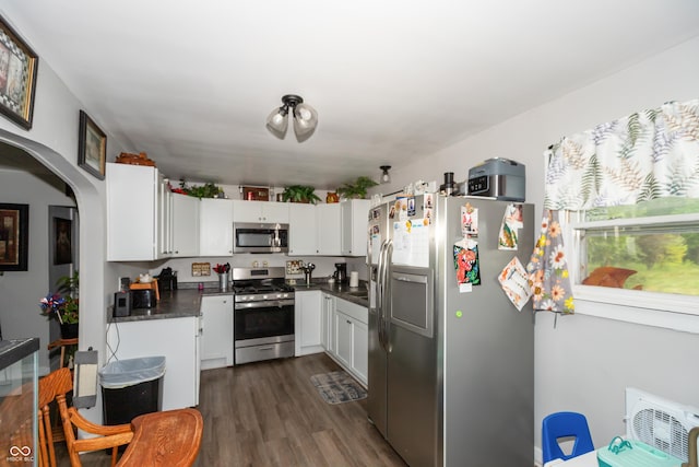 kitchen featuring visible vents, white cabinets, dark countertops, appliances with stainless steel finishes, and dark wood-type flooring