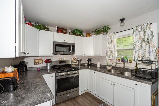 kitchen with dark hardwood / wood-style flooring, stainless steel appliances, sink, and white cabinets