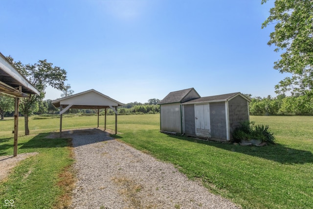 view of yard featuring a storage unit, an outdoor structure, a detached carport, and gravel driveway