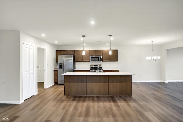 kitchen featuring a kitchen island with sink, dark wood-type flooring, sink, pendant lighting, and stainless steel appliances