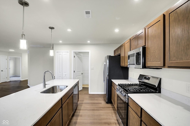 kitchen featuring hardwood / wood-style flooring, appliances with stainless steel finishes, sink, and decorative light fixtures