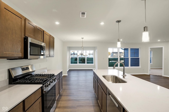 kitchen with a chandelier, dark hardwood / wood-style floors, sink, decorative light fixtures, and stainless steel appliances